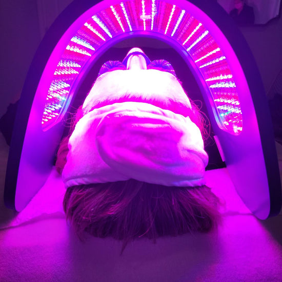 Client laying on treatment bed with an LED device giving her a LED treatment to treat her skin concerns
